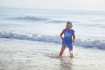 Little happy girl have fun on the sea, she runs and laughs