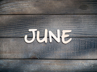 The name of the month is composed of light wooden letters on dark wood. The month of June.