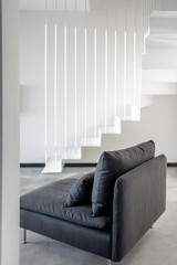 Geometric view of white interior with metal stairway and gray sofa