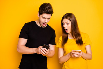 Photo of two people outraged angry seeing fake news spreading browsing through social media watching information being posted in black t-shirt isolated vibrant shiny yellow color background