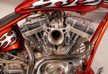 Fototapeta na wymiar v-type two-cylinder motorcycle engine with chrome coating. Orange motorcycle frame with white flames.