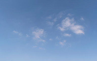 abstract cloudscape of small wispy puffy clouds in a clear blue sky with a little haze at the bottom
