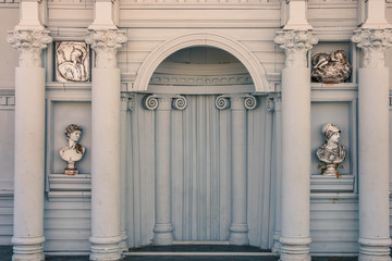 Fragment of the building facade with arched windows and white columns.