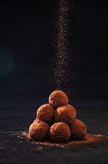 Homemade Chocolate Truffles in Glass with Sifting Cocoa on Dark Stone Table and Background. Copy...