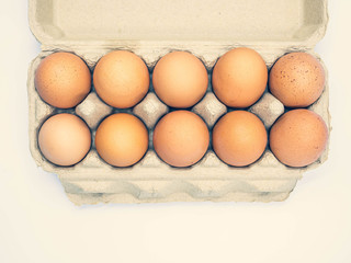 Top view or directly above of cross processed tone of chicken brown eggs in paper box on gradient background for cooking, dieting, healthy eating, nutrition and Easter holidays concepts and ideas.