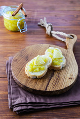 Cucumber jam with lemon and bread on a wooden board.