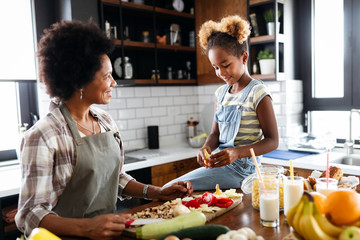 Mother and child having fun preparing healthy food in kitchen