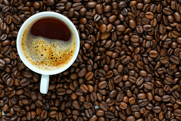 Freshly brewed coffee in a cup with coffee beans.