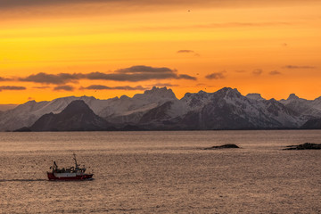 fishing boat with amazing sunset in background in lofoten, norway.