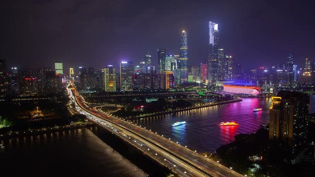 Timelapse famous illuminated Guangzhou Middle Avenue goes into bridge over calm Pearl river reflecting coloured cityscape in Guangdong province of China at night