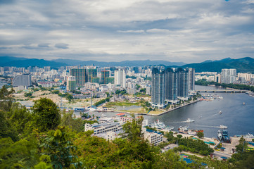 Fototapeta premium Top View of Hainan's Sanya City, with local houses and luxury hotels and buildings. Summer Vacation Paradise in Asia.