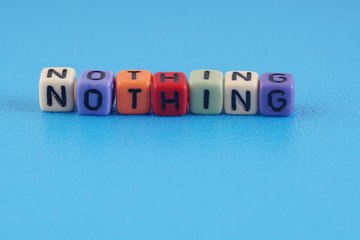 A word NOTHING made by a colourful cube beads alphabet  over blue background.