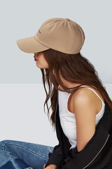 Cropped side photo of a girl, wearing white baseball cap with lettering 