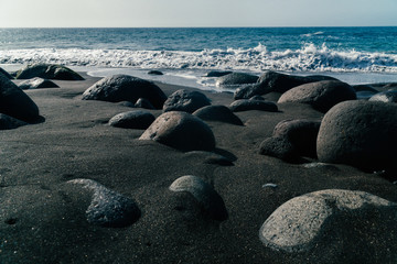 Low shot of black sand beach Playa de Guayedra in Las Palmas on Gran Canaria volcanic island, Spain, Atlantic ocean