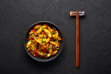 Baby Corn Manchurian dry looks like Schezwan Baby Corn in black bowl at dark slate background. Baby Corn Manchurian - is indo chinese cuisine dish with deep fried corn, bell peppers, sauce and onion.