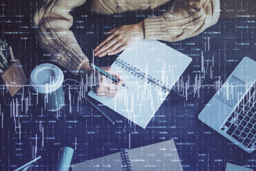 Forex graph on hand taking notes background. Concept of research. Double exposure