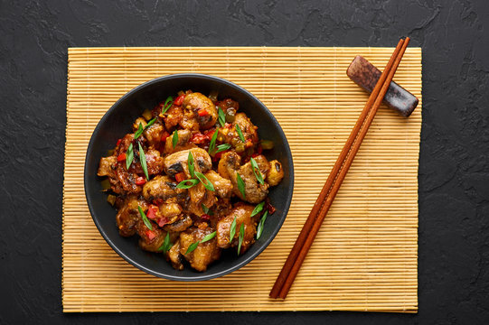 Mushrooms Manchurian dry in black bowl at dark slate background. Mushroom Manchurian - is indo chinese cuisine dish with deep fried mushrooms, bell peppers, sauce and onion.