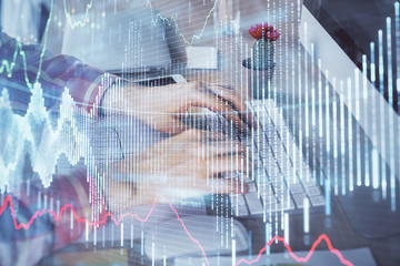 Double exposure of stock market chart with man working on computer on background. Concept of financial analysis.