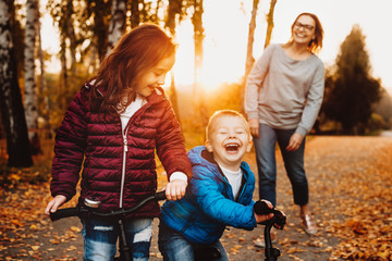Portrait of a brother and sister playing with their bicycles outdoor against sunset laughing.