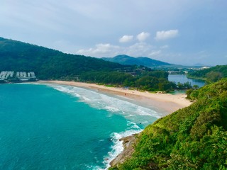 Fototapeta premium Wind turbine Panorama drone aerial view electricity windmill overlooking Naiharn beach phuket Thailand turquoise blue waters white golden sandy beach lush green mountains 