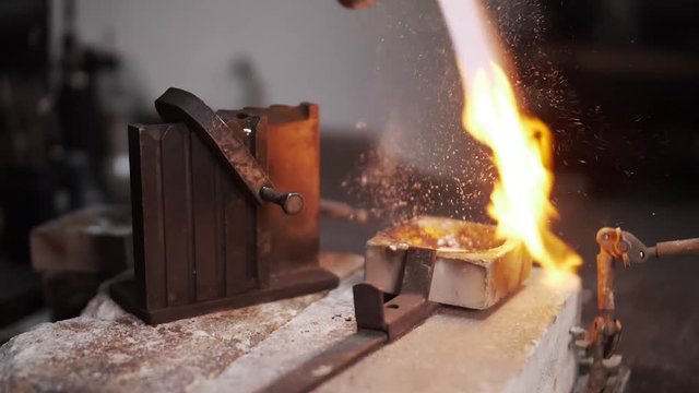 Closeup of hand putting borax powder while smelting gold