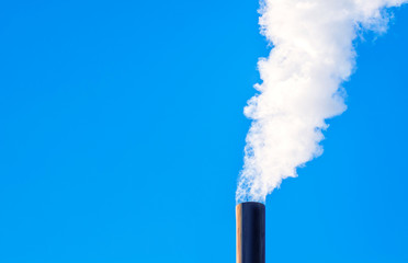 Industrial smoke from the pipe on a blue sky background. Environment pollution and global warming...