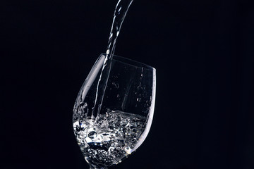 Pouring water into a glass on a dark background
