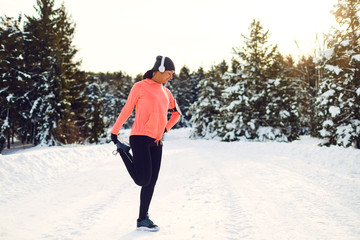 Young woman stretching before running in the winter park