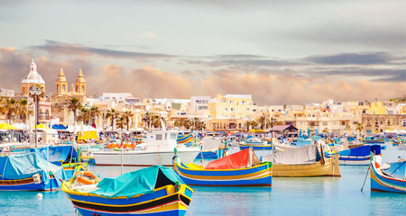 Fisherman port village in Marsaxlokk Malta. Mediterranean traditional retro colorful boats luzzu on...