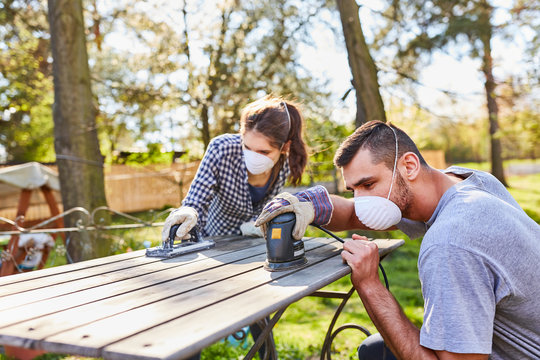 Couple Doing Home Improvement In The Garden With Grinder