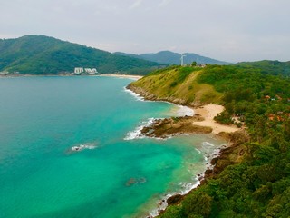 Wind turbine  Panorama drone aerial view electricity windmill overlooking Naiharn beach phuket Thailand turquoise blue waters white golden sandy beach lush green mountains 