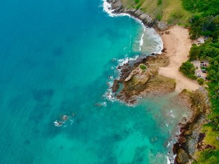 Wind turbine  Panorama drone aerial view electricity windmill overlooking Naiharn beach phuket Thailand turquoise blue waters white golden sandy beach lush green mountains 