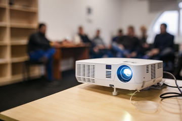 LCD video projector at business conference or lecture in a conference room or office with blurred people background - obrazy, fototapety, plakaty
