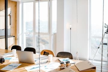 Workplace with large wooden table and office supplies with no people in bright sunny office room