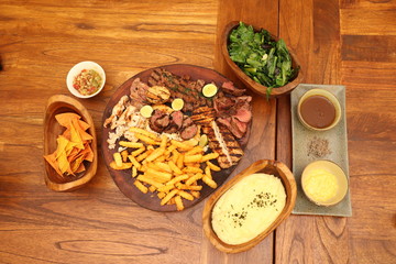 various spices and herbs, meat, chicken, steak, fish, fries, mash potato on wooden table