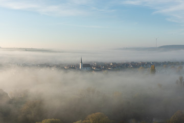 Blick von den Weinbergen auf Escherndorf und seine Kirche im Nebel