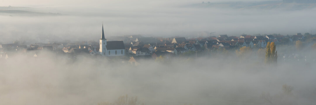 Blick von den Weinbergen auf Escherndorf und seine Kirche im Nebel