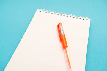 school white notebook with pen on blue background