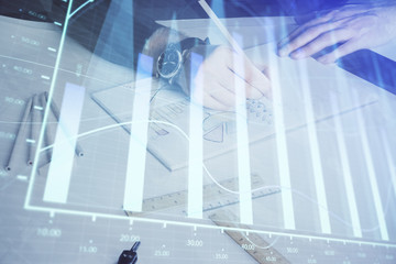Double exposure of man's hands writing notes of stock market with forex chart.