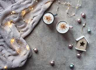 Magical winter composition. Winter concept. Cups of coffee, lights, warm knitted scarf.