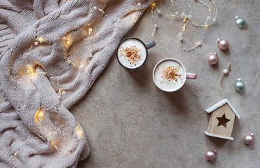 Magical winter composition. Winter concept. Cups of coffee, lights, warm knitted scarf.