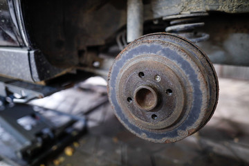 Shallow depth of field (selective focus) image with a rusty rear wheel hub of an old car.