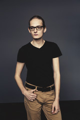 An attractive man in glasses with his hands on a gray background.