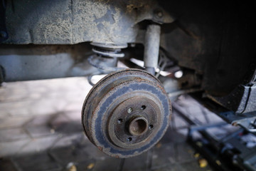 Shallow depth of field (selective focus) image with a rusty rear wheel hub of an old car.