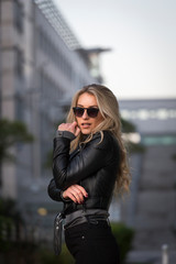 Frau, jung, blond ,schön, modisch, modebewusst und schlank geht im Herbst mit Lederjacke und engen...