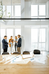 Group of young business people working and having some discussion in the spacious meeting room with...