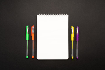 Fototapeta na wymiar school white notebook with pen on black background