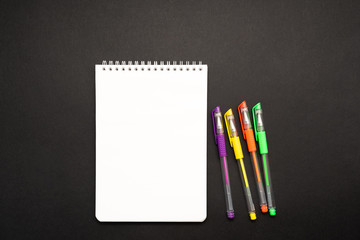 school white notebook with pen on black background