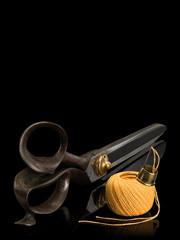 Ancient, professional scissors of the cutter, hank of yellow threads, thimble and needle