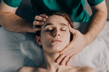 Fototapeta na wymiar Male massage therapist makes face massage to a young beautiful woman.